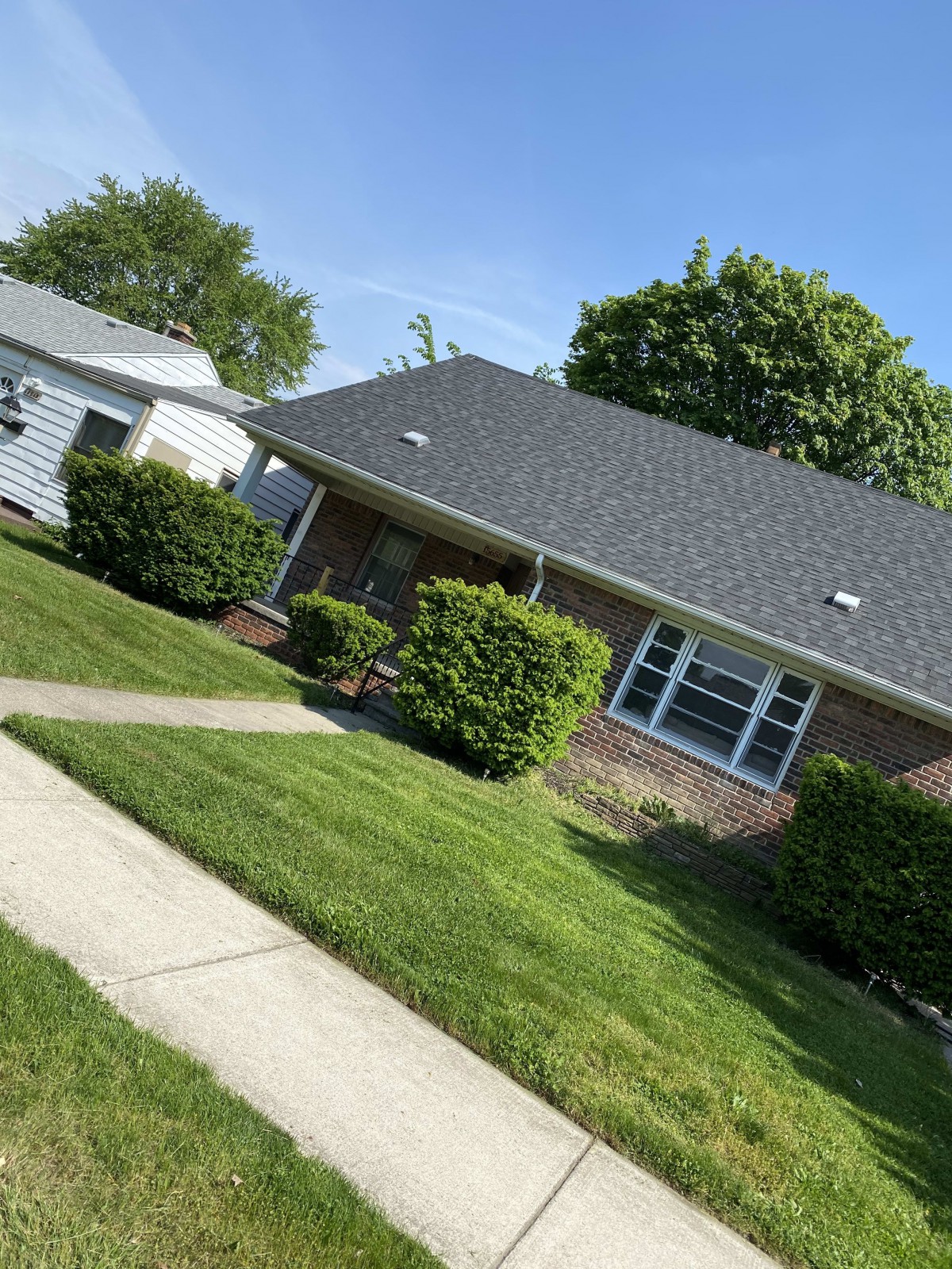 A suburban house with a well-maintained lawn and sidewalk on a sunny day.