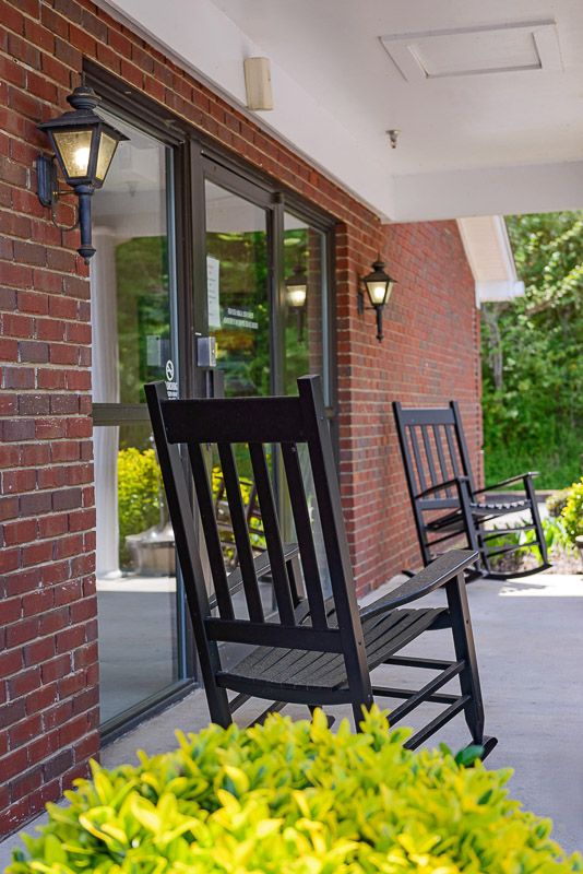 A cozy porch with black rocking chairs and brick walls.