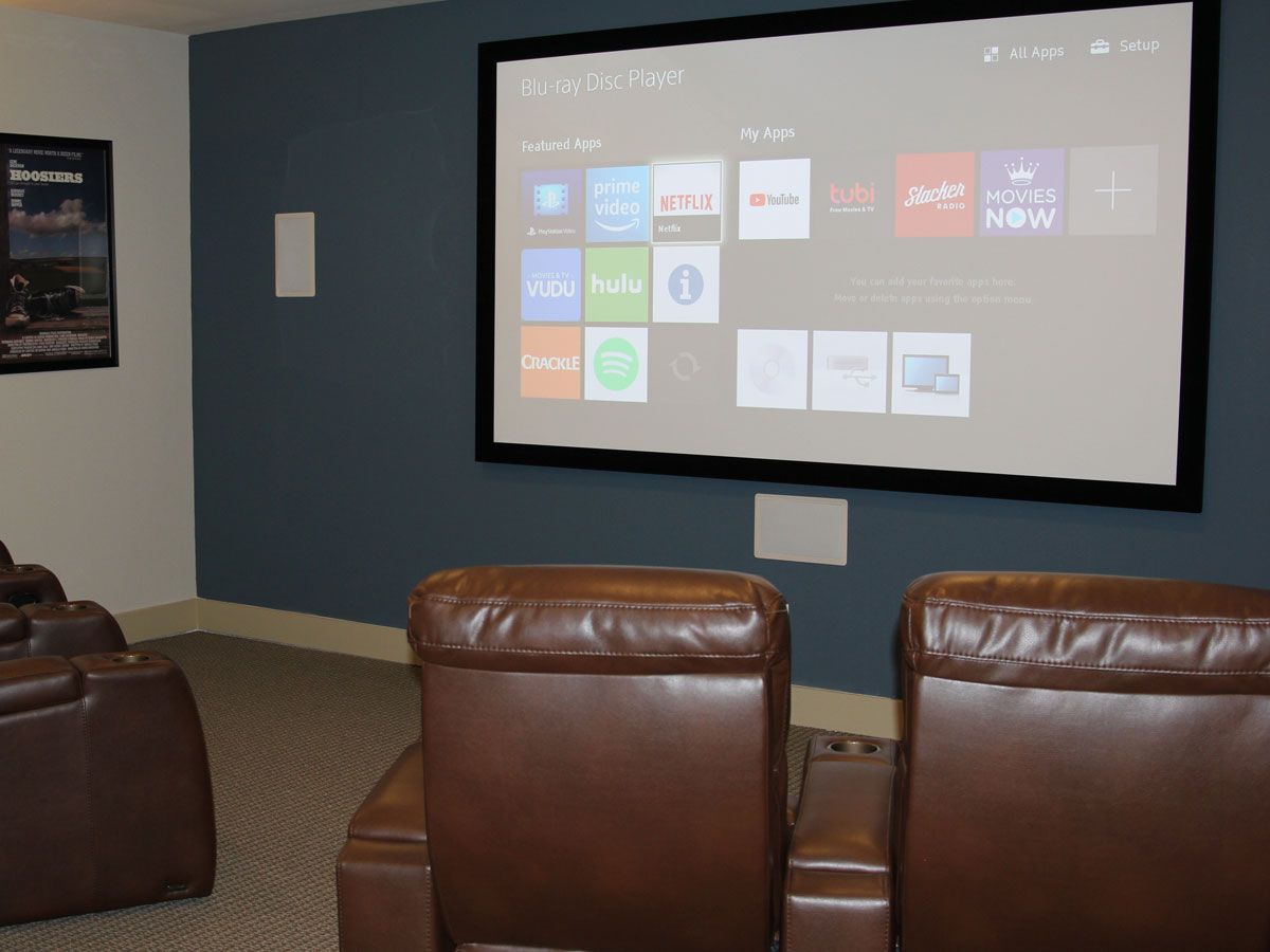 Cozy home theater room with leather recliners and a large projector screen.