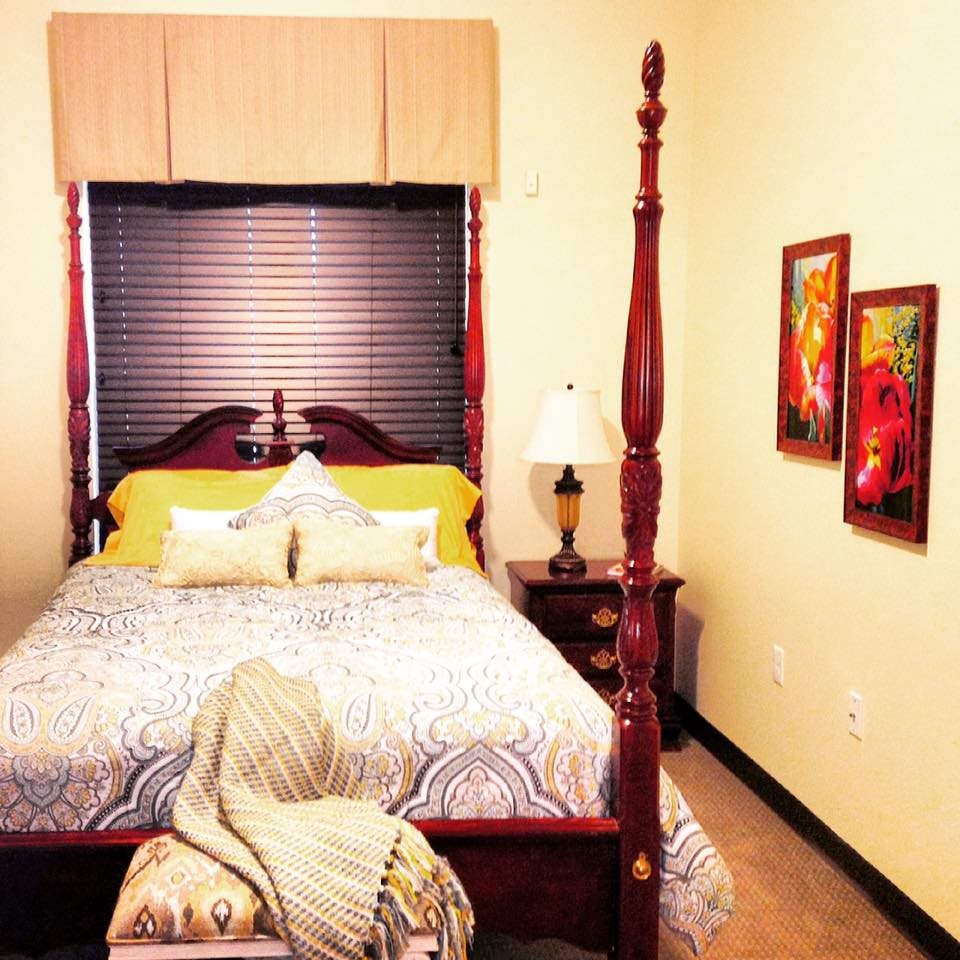 A cozy bedroom with a four-poster bed and vibrant artwork.