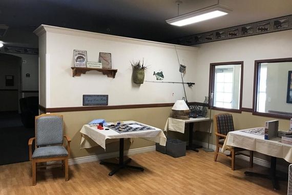 A cozy room with fishing-themed decorations, featuring tables, chairs, and a wooden floor.