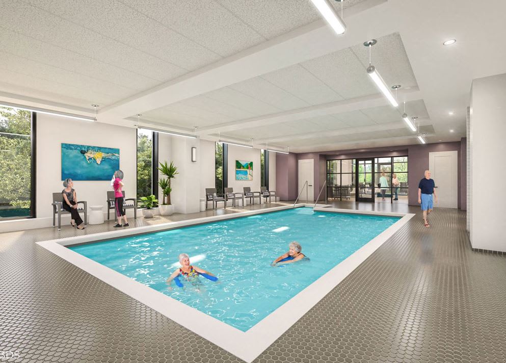 An indoor swimming pool with people enjoying a swim and relaxing by the poolside.