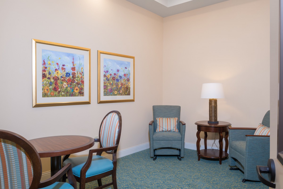 A cozy living room corner with a chair, side table, and decorative artwork on the wall.