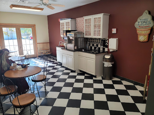 A modern kitchen with a checkered floor and coffee station, featuring simple dining furniture.
