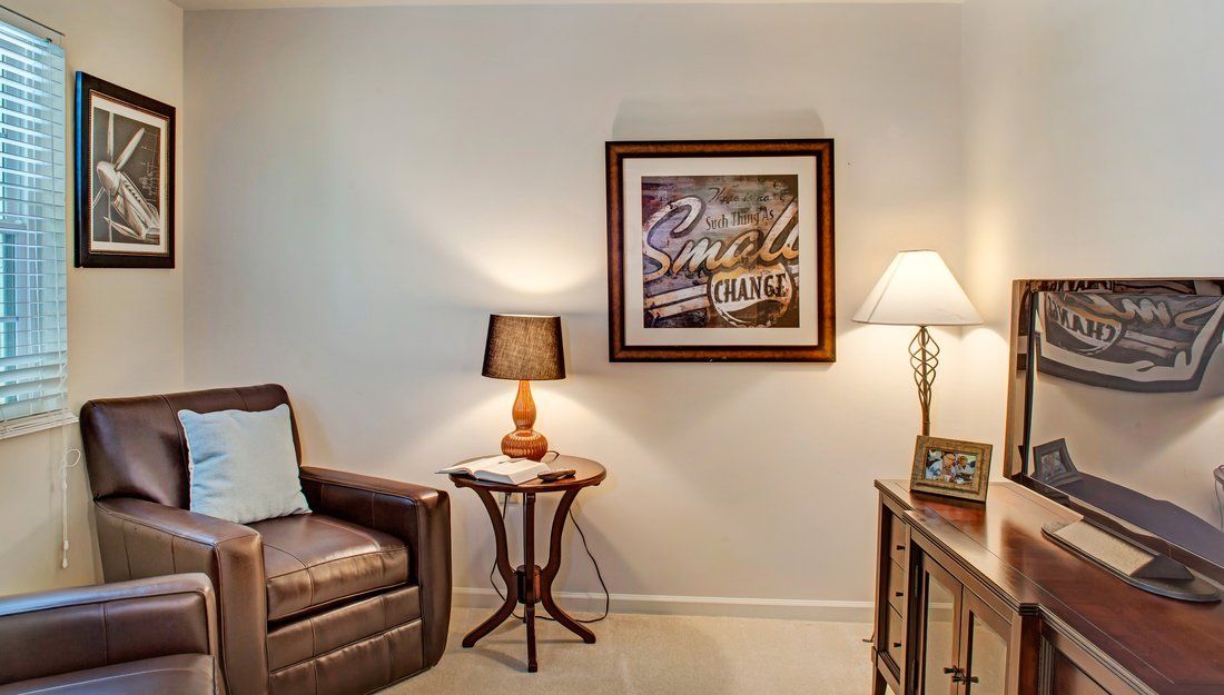 A cozy living room corner with a leather chair, two lamps, and decorative artwork on the wall.