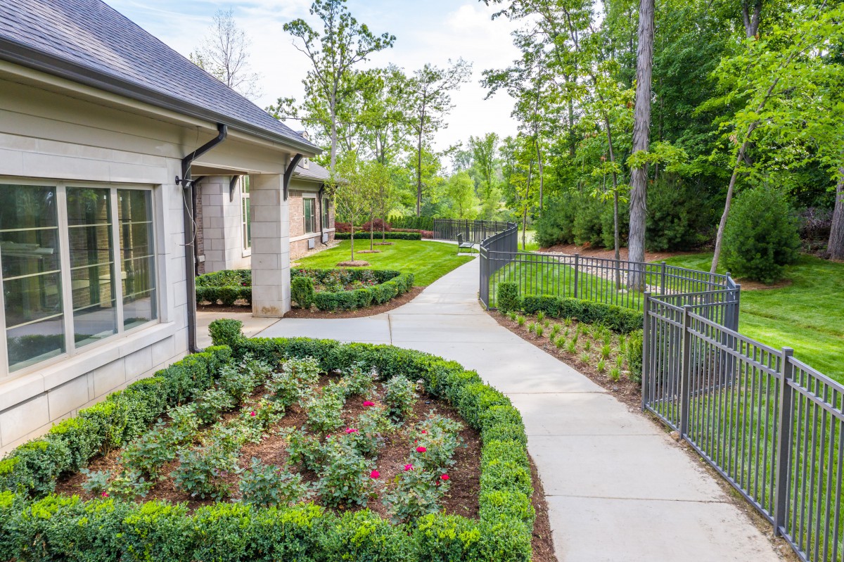 A beautifully landscaped garden with a sidewalk winding through manicured shrubbery and trees.