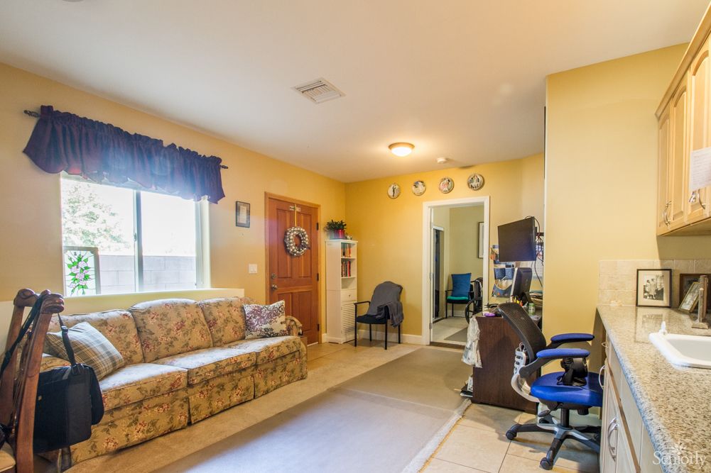 A cozy living room with a sofa, desk, and chairs, featuring a home office setup.