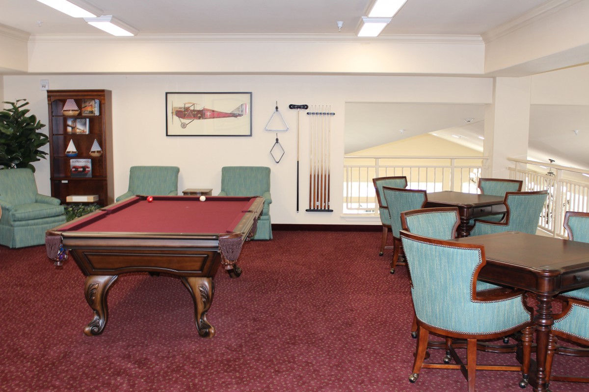 A cozy game room with a pool table and seating area on red carpet.