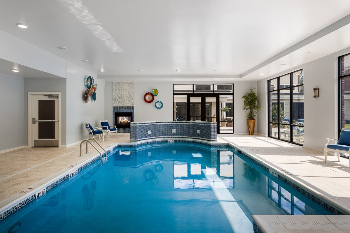 A well-lit indoor swimming pool with modern decor and large windows.