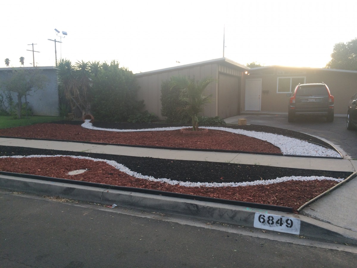 A modern xeriscape front yard with curved rock patterns and a minimalistic design.