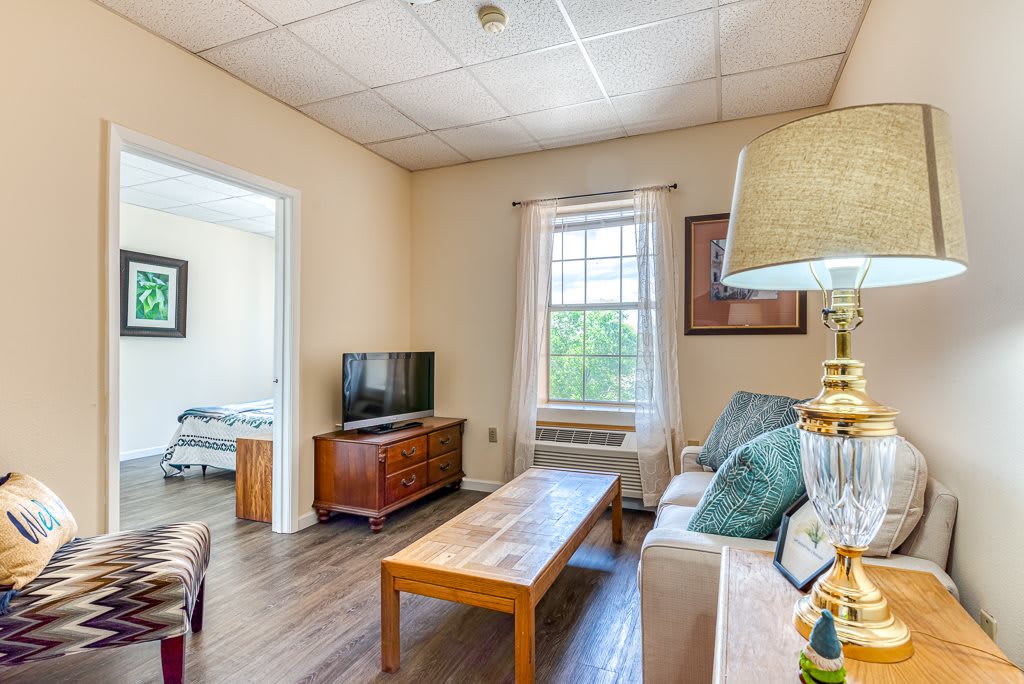 A cozy living room with a TV, sofa, and coffee table near a window.
