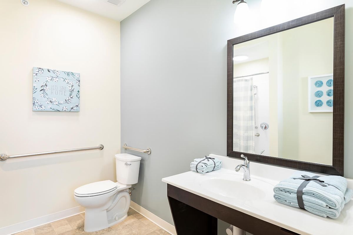 A modern bathroom interior with a sink, mirror, and toilet.