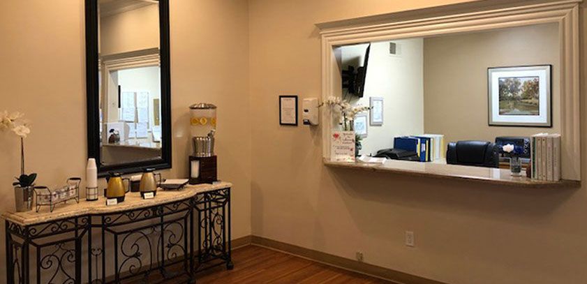 A view of a waiting room with a reception window and a water dispenser.