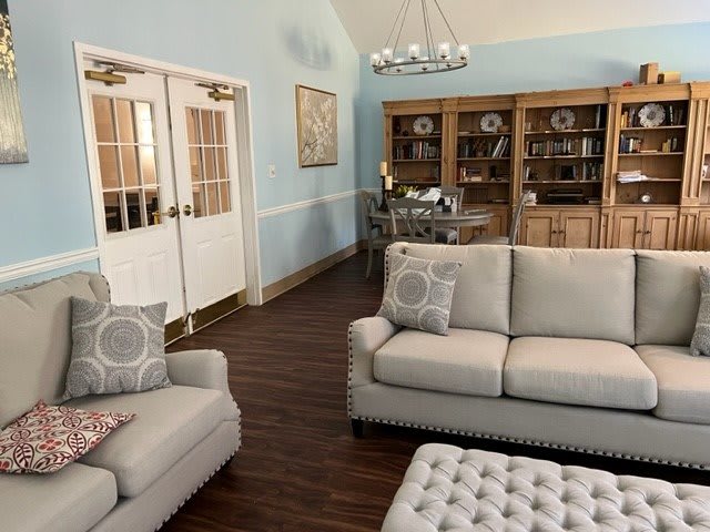 A well-decorated living room featuring comfortable sofas, a large bookcase, and a chandelier.