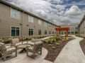 Outdoor patio area with seating and landscaping in front of a modern building.