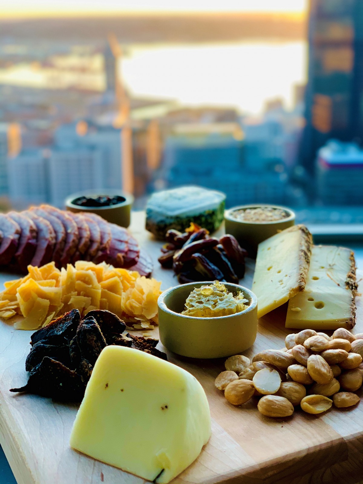 A gourmet cheese and charcuterie board with a cityscape backdrop.