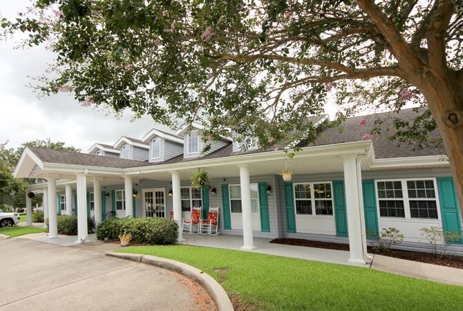 A single-story house with a covered porch and surrounding greenery.