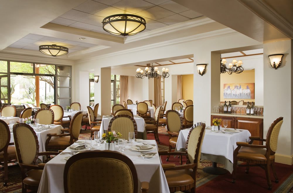 A well-lit, elegantly decorated restaurant dining room with neatly arranged tables and chairs.