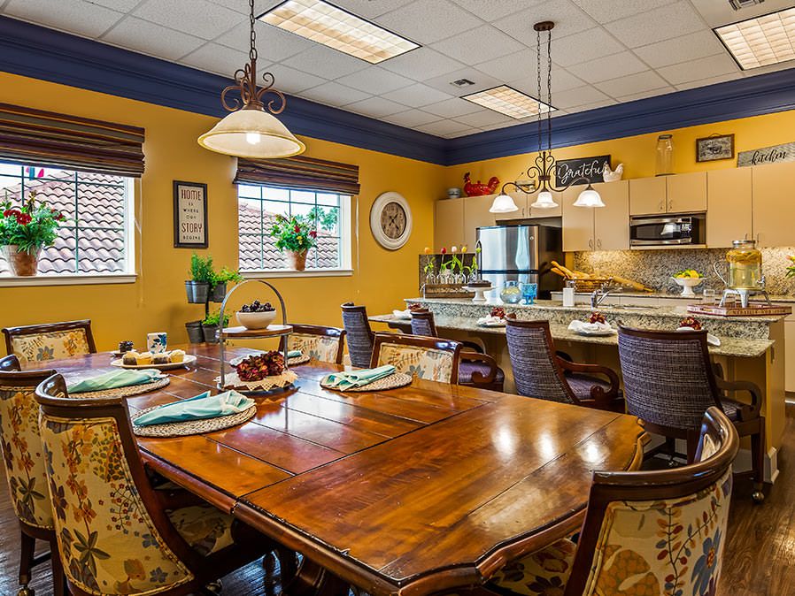 A cozy kitchen and dining area with a large wooden table, pendant lights, and decorative accents.