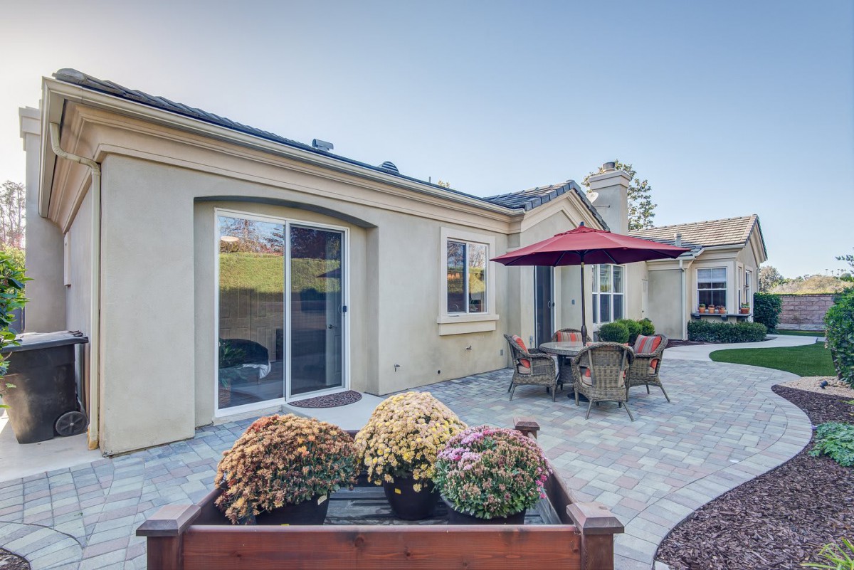 A cozy patio area with outdoor seating and a large umbrella, situated next to a house.