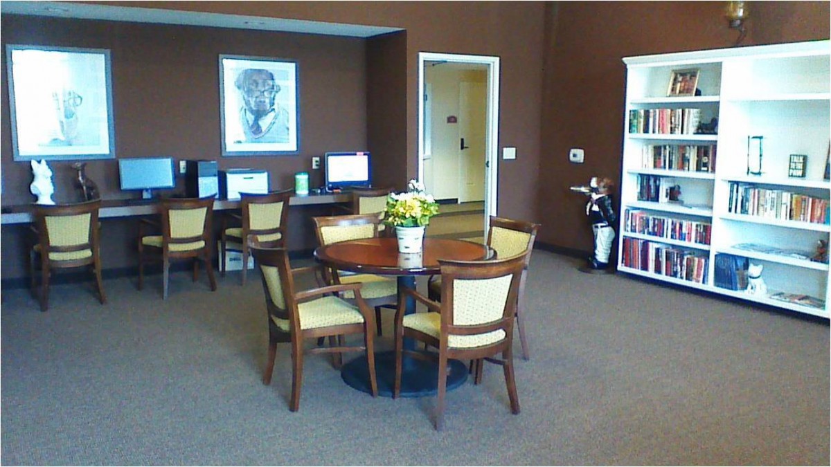 An office space with computers, a round meeting table, chairs, and a bookshelf.