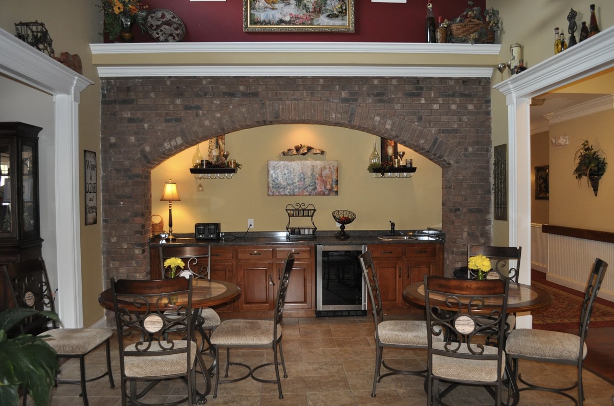 A cozy kitchen and dining area with a brick archway and wooden cabinetry.
