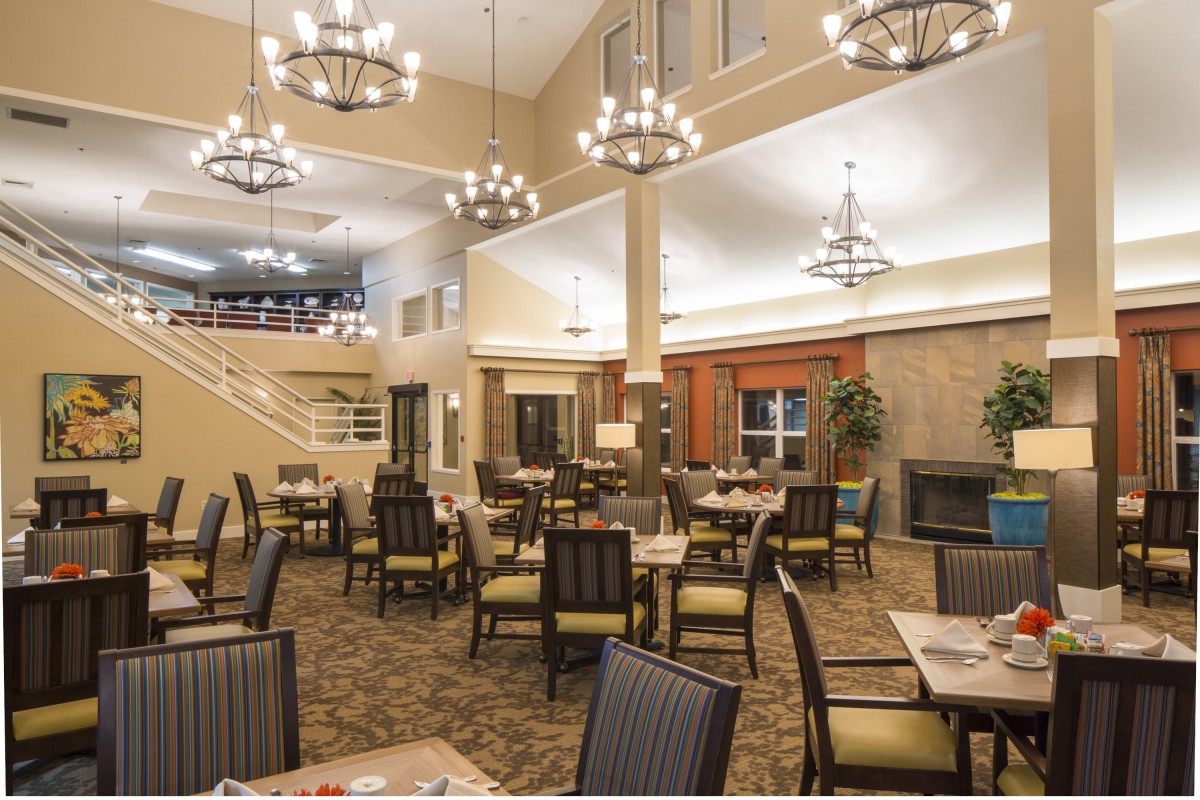 A spacious dining area with elegant chandeliers and neatly arranged tables and chairs.