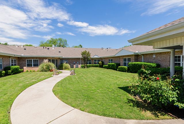 A well-maintained building with a garden and pathway under a clear blue sky.
