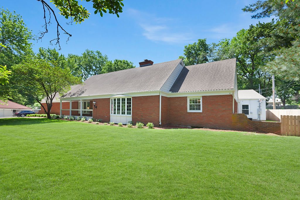 A brick house with a well-maintained lawn and a clear blue sky.