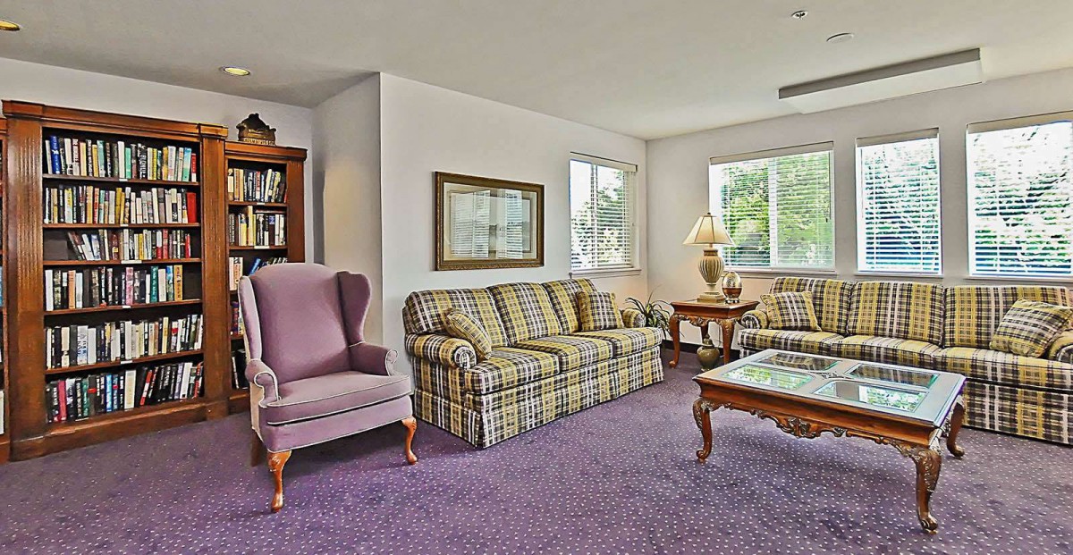 A cozy living room with a plaid sofa, armchair, and large windows.