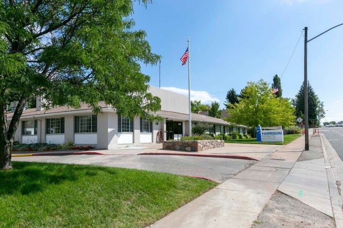 The exterior of a healthcare facility with flags and surrounding greenery on a sunny day.