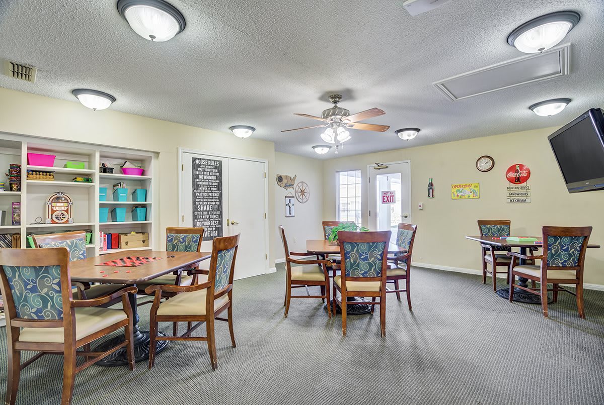 A well-lit dining area featuring multiple tables and chairs, with colorful shelving in the background.