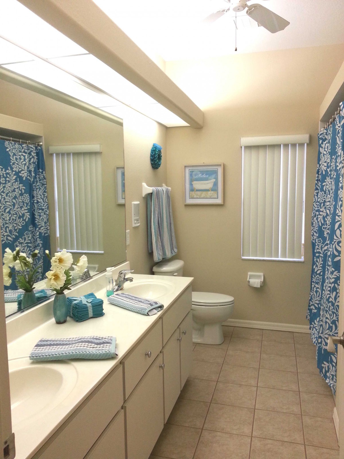 A neatly organized bathroom with blue accents and a large mirror.