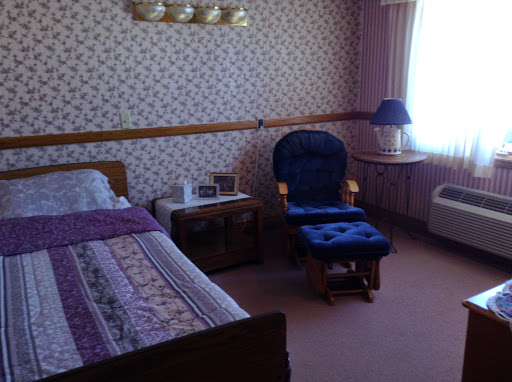 A cozy and traditional bedroom featuring a bed, a lounge chair, and soft lighting.