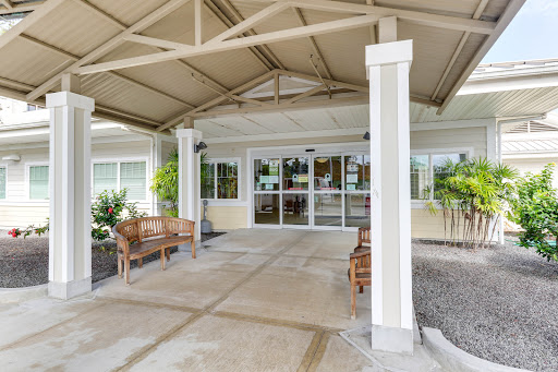 The welcoming entrance of a facility with outdoor seating and a protective canopy.