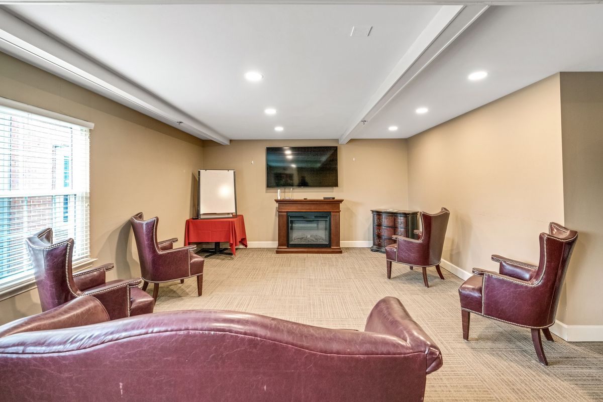A cozy basement living area featuring comfortable seating around a television and fireplace.