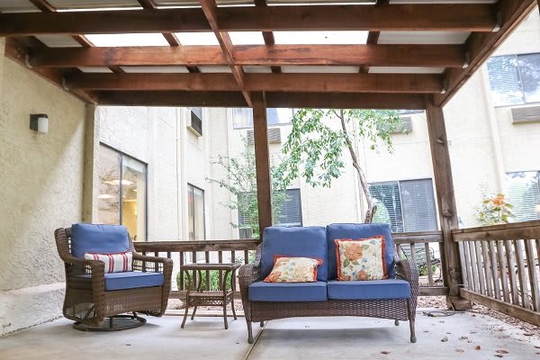 A cozy outdoor patio featuring wicker seating with blue cushions under a wooden pergola.