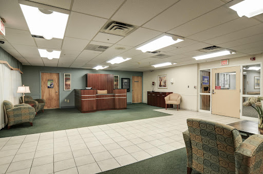 A spacious office lobby with a reception desk, comfortable seating, and a mix of tile and carpet flooring.