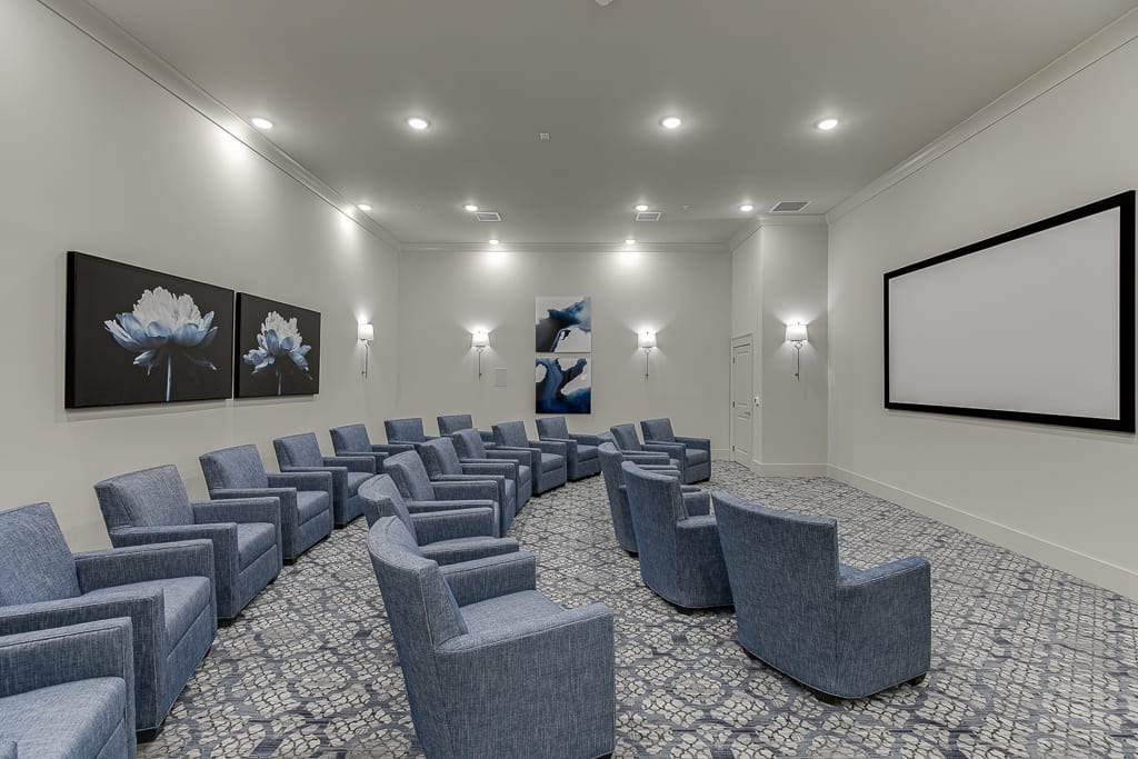A modern home theater room with comfortable armchairs and a large projector screen.