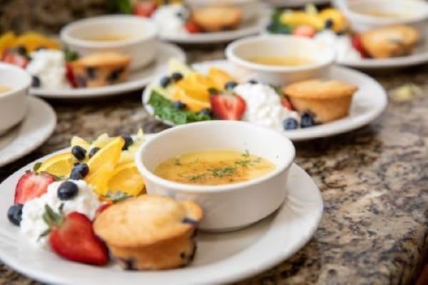 A delectable breakfast spread featuring crme brle, muffins, and fresh fruit.