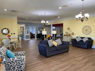 A cozy and well-lit living room featuring comfortable sofas, elegant chandeliers, and a wooden floor.