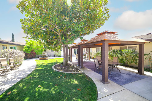 A beautiful outdoor space featuring a well-maintained garden with trees and a shaded patio area.