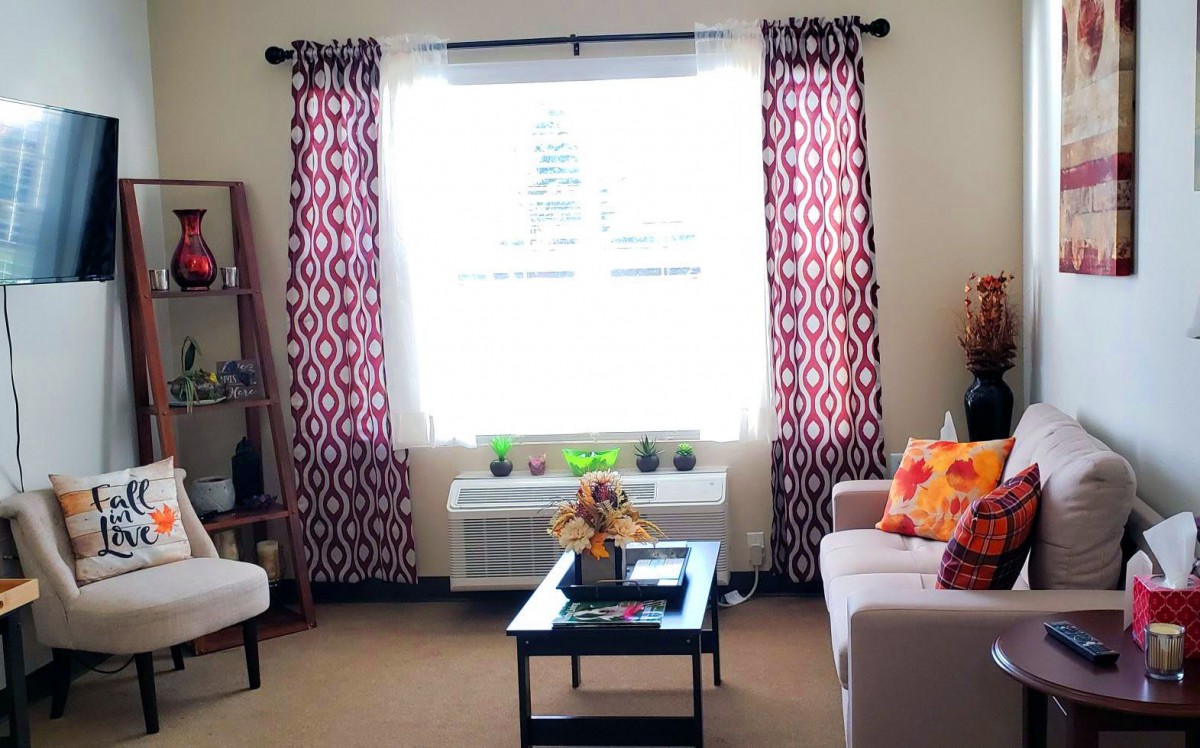 A cozy living room with patterned curtains, a coffee table, and sofa seating.