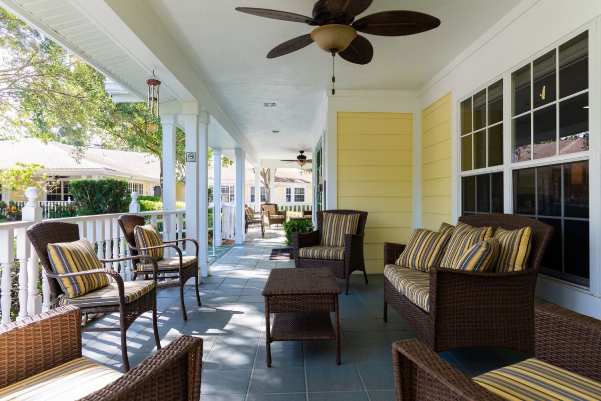 A spacious porch with comfortable seating and a ceiling fan, perfect for enjoying a sunny day.