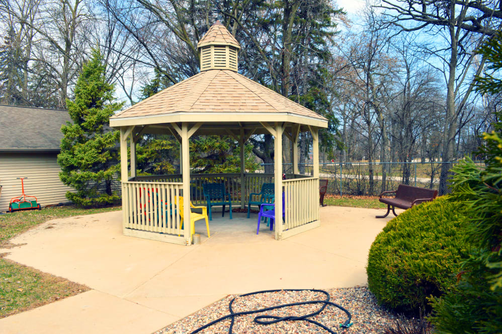 A peaceful gazebo surrounded by colorful chairs in an outdoor setting.