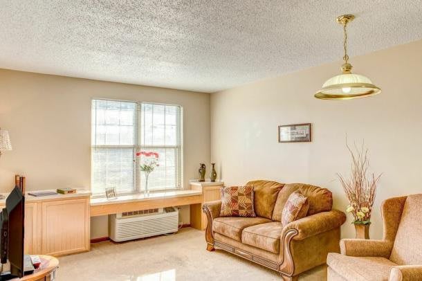 A cozy living room with a comfortable sofa and bright natural light from a large window.