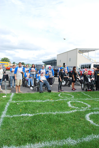 A lively outdoor event with a diverse crowd participating in various activities on a grassy field.