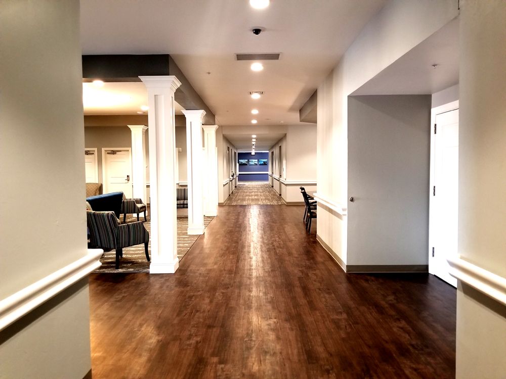 A well-lit hallway with wooden flooring and white columns.
