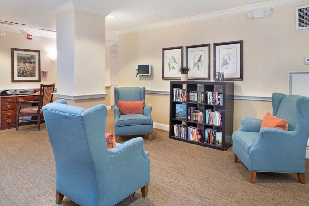 A cozy reading area with blue armchairs and a well-stocked bookshelf.
