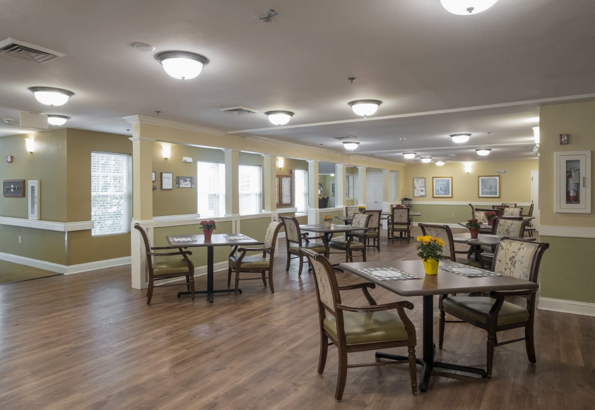 A well-lit dining area with neatly arranged tables and chairs on a wooden floor.